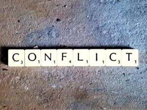 Scrabble tiles spelling the word "conflict" on stone.