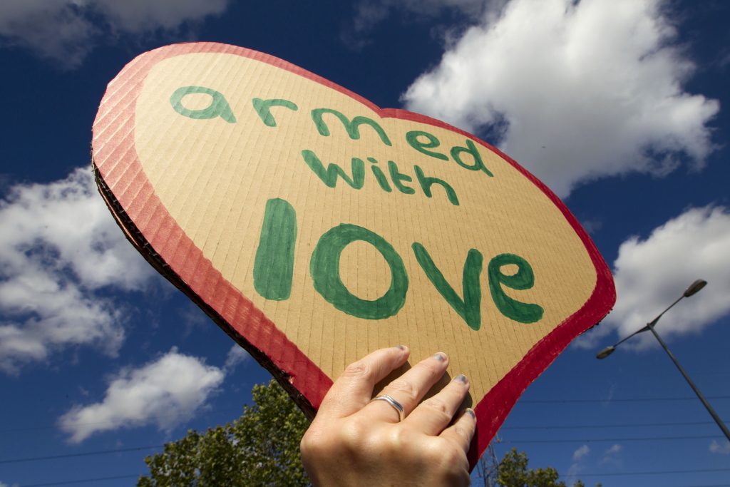Handmade sign in shape of heart, writing says 'armed with love'.